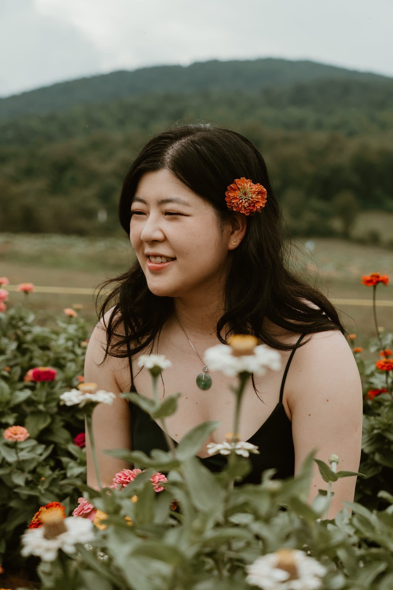 Katie in a field of zinnias, a flower tucked behind her ear